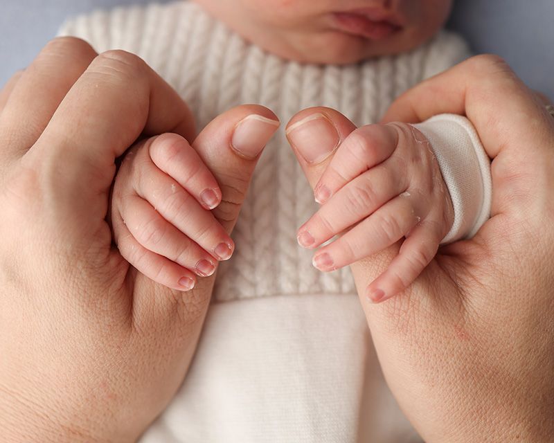 Woman's hands holding a newborn. Therapy for perinatal mental health in Irvine, CA.