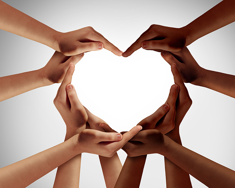 Multicultural group of people forming a heart shape with their arms